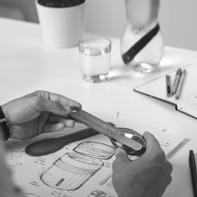 Designer admiring cutlery set and image of thermos hand drawn design