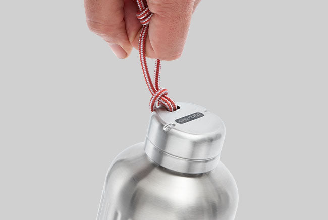 hand dangling stainless steel vacuum insulated explorer bottle from paracord carry loop
