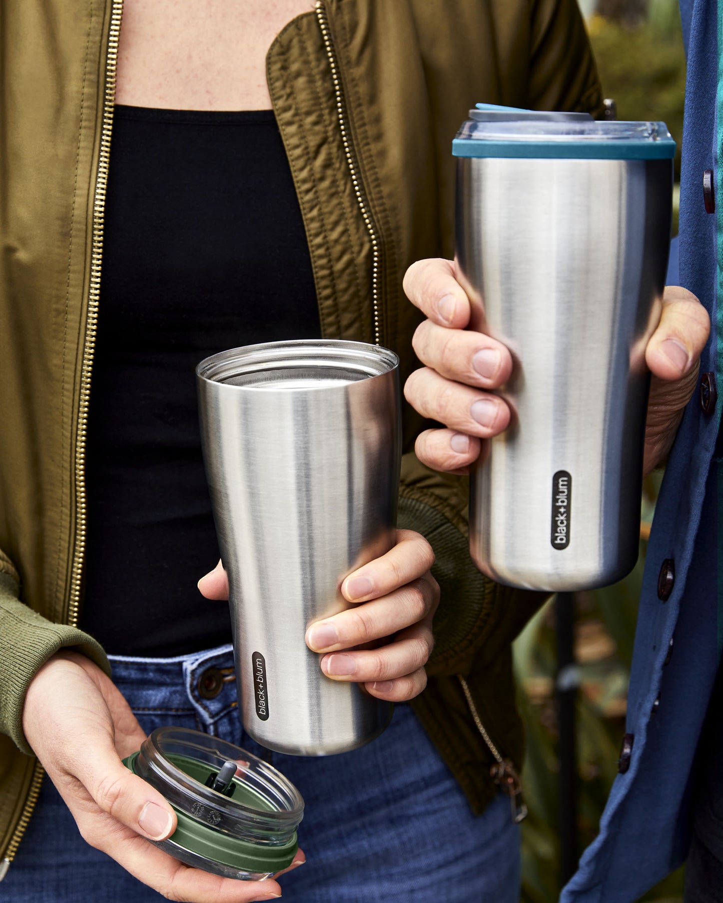 Two insulated tumblers being held